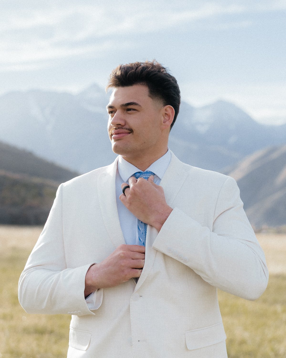 Blake Soifua in a cream suit, mountains behind